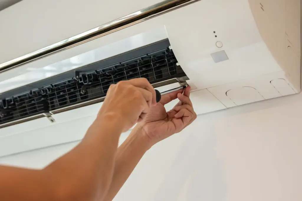 Technician cleaning a split-system air conditioner filter